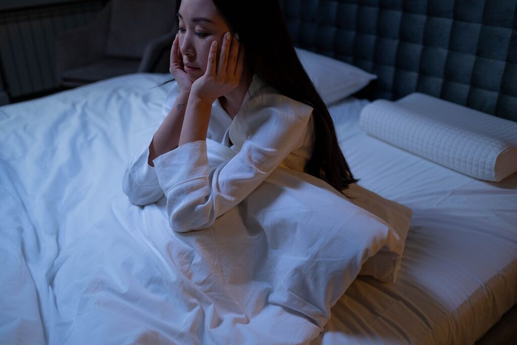 Femme assise sur son lit la nuit, troubles du sommeil liés à la ménopause