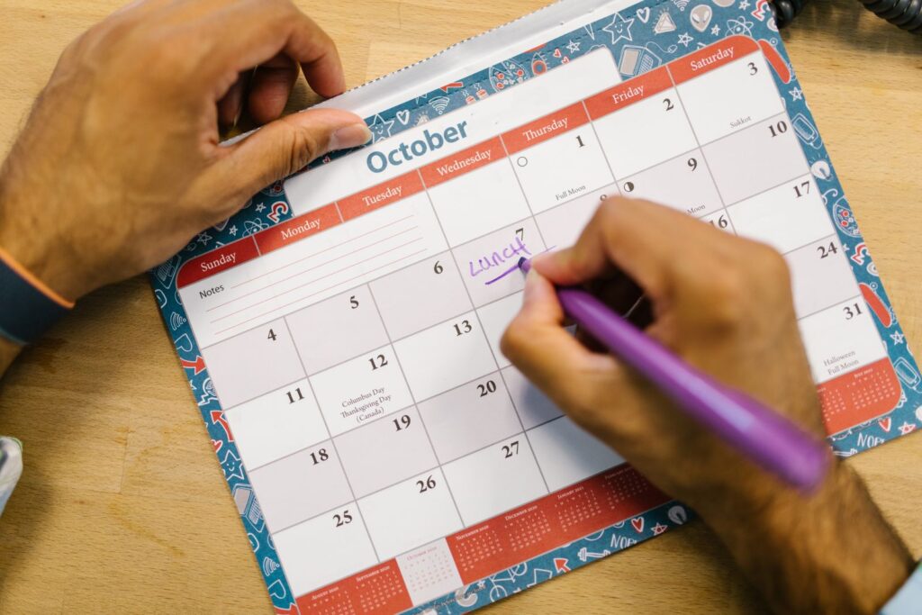 Main notant les dates sur un calendrier pour suivre des règles irrégulières en préménopause
