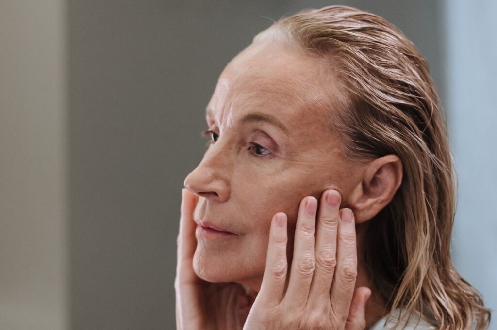 Femme mûre appliquant un soin du visage, peau et cheveux à la ménopause